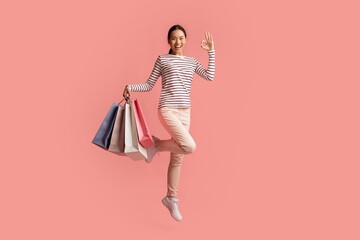 Big Sales Concept. Happy Asian Female Jumping With Shopping Bags And Showing Ok Gesture, Excited Young Korean Woman Enjoying Seasonal Discounts, Posing Isolated Over Pink Background, Copy Space