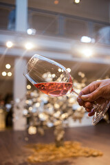 A hand holding a Rose wine in movement in a wineglass in first pane High quality photo