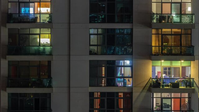 Windows of apartment building at night timelapse, the light from illuminated rooms of houses