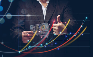 businessman in a suit holds a pack of paper american dollars against the background of a holographic chart with growing indicators. The concept of high business profitability, income growth
