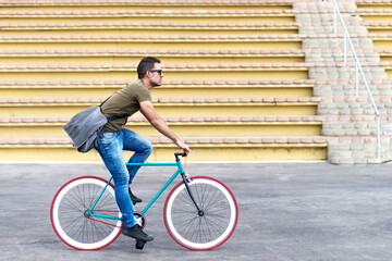 Man with sunglasses riding bicycle in urban city commuting trendy transportation