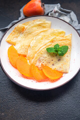 persimmon thin pancakes fruit crepe breakfast sweet dessert healthy meal food snack on the table copy space food background 