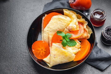 persimmon thin pancakes fruit crepe breakfast sweet dessert healthy meal food snack on the table copy space food background 