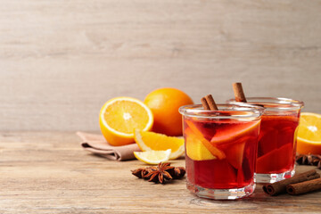 Aromatic punch drink and ingredients on wooden table, space for text