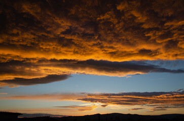 Lush, heavy clouds, painted orange by the sun at sunset. Texture.