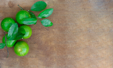 Fresh lime (lemon) and green leaf on wooden background.