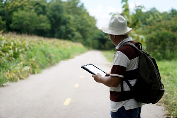 Asian male tourist stand alone on street in rural, checking route , internet signals and  map application on smart tablet. Concept : Using wireless technology device.  