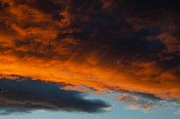 Lush, heavy clouds, painted orange by the sun at sunset. Texture.