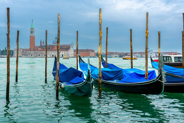 Fototapeta premium December 2, 2021 - Venice, Italy: Gondolas moored at Sam Marco Gondola Service Station on Grand Canal with Chiesa di San Giorgio Maggiore on the background.