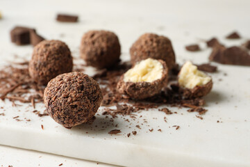Many delicious chocolate truffles on white board, closeup. Space for text