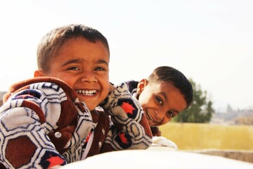 Two Pakistani kids who are laughing a lot, Selective focus on one child, winter season  - obrazy, fototapety, plakaty