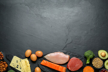 Different fresh products on black table, flat lay and space for text. Sources of essential amino...