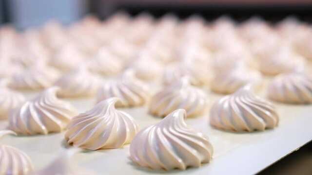 Fresh creamy marshmallows moving along the conveyor belt at the confectionery factory. Close up. Blurred background.