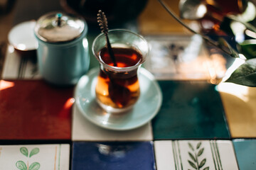 Turkish tea in traditional glass on the table decorated with colorful ceramic tiles