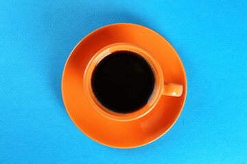 Coffee in cup on light blue background, top view