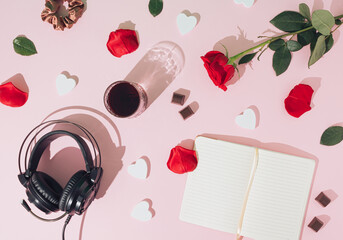 Creative romance arrangement made of red rose, glass of drink and headphones on a pink background. Minimal retro flat lay concept. Love and Valentine's Day inspiration. Copy space.