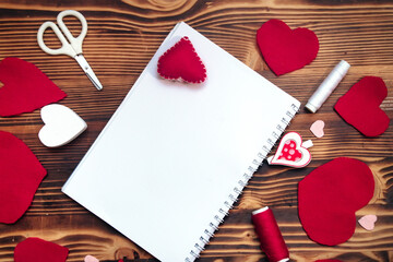 Empty notepad on spring on wooden table. Hand-sewn red hearts. Letter to Valentine's Day concept. Congratulations with Valentine.