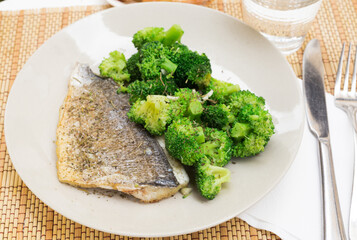 dish of fried dorado fish fillet with boiled broccoli