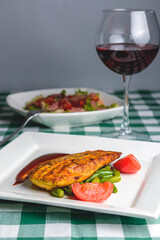 Grilled chicken breast with cherry tomatoes, green French beans, garlic, herbs, served on a white plate