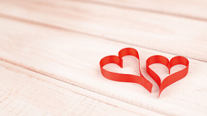 Two red hearts from a ribbon on a wooden background. Valentine's day, love concept