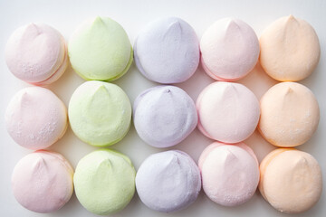 Delicate pattern of multi-colored pastel marshmallows on a light background, top view, flat lay. Pastel marshmallows as a background. Sweets and food background