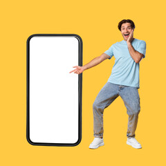 Excited man showing white empty smartphone screen and pointing