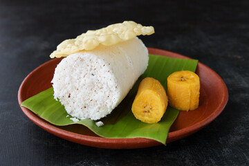 Popular South Indian breakfast puttu / pittu made of rice flour and coconut with banana and kadala curry, Kerala breakfast, India. Bamboo puttu prepared in steam 