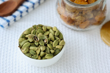 Heap of fresh organic green cardamom pods spice Indian spices for Indian cooking Masala hot spicy curry whole spices wooden spoon leaves Kerala India Sri Lanka.