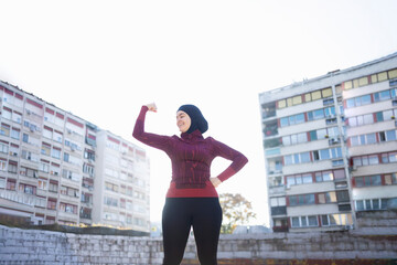 Young and happy Muslim woman expressing her strength - obrazy, fototapety, plakaty