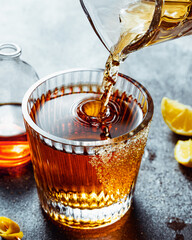 pouring whiskey in glass with Old fashion coktail drink with brown sugar and lemon. vertical shot