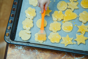 smear cookies on baking sheet and parchment with an orange silicone brush