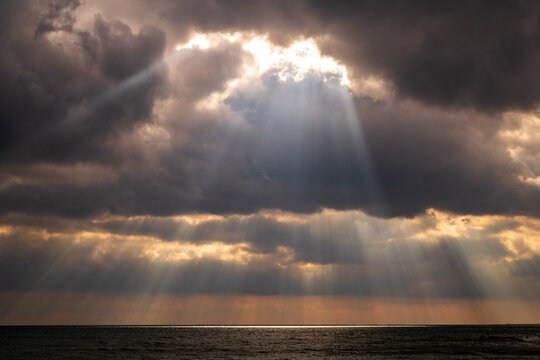 Pillars of lights and dramatic clouds over Lake Ontario with rocks, waves and ice. Suitable for background, space for text.