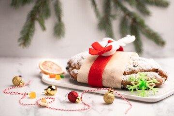Christmas baking cake stollen on the festive table. Decorated with spruce branches and Christmas tree toys. Table setting for the holiday