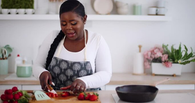 happy young woman cooking on the kitchen at home and singing