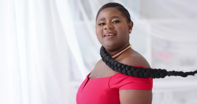 happy young african american woman with long hair braid whirling around on white cloth background