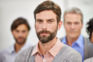 Confident in his team-leading abilities. Cropped shot of a handsome young man standing with his colleagues blurred in the background.