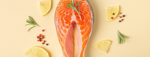 Uncooked raw fresh fish salmon steak top view on beige pastel background with rosemary, lemon...