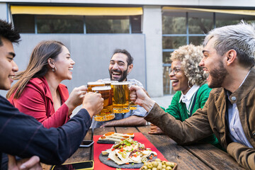 Happy young friends toasting pint beer celebrating friendship together in outdoors bar