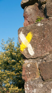 Señal blanca y amarilla de ruta en muro de piedra