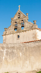 Campanario de iglesia medieval tras muro de piedra