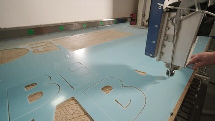 CNC cutting machine at work, cutting acrylic plastic sheets. Production of advertising signs
