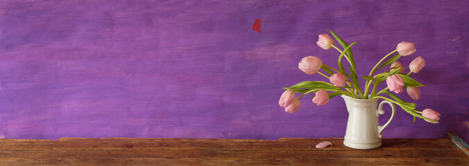 bunch of tulips in an old mug, almost faded flowers,panoramic,large copy space