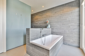 Interior of bathroom with built in tiled bathtub opposite window