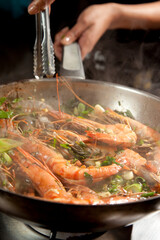 Fresh prawn, or shrimp being pan fried with celantro and herbs in a pan.