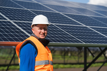 Portrait of male electrical engineer on the background of solar panels at a power plant