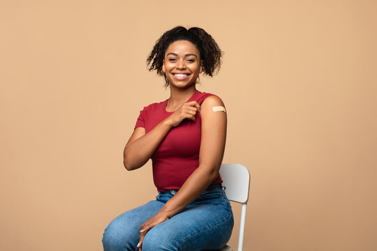 Coronavirus Vaccination. Joyful Black Woman With Band Aid On Shoulder Proud Of Making Covid Vaccine On Beige Background