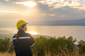 a woman engineer is putting a protective helmet on her head at sunset.