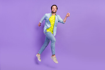 Fototapeta na wymiar Full size photo of jumping smiling guy running fast speed traveling enjoy free time isolated on violet color background