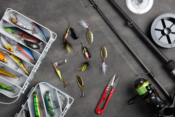 Fishing tackle - fishing spinning rod, hooks and lures on gray background. Active hobby recreation concept.