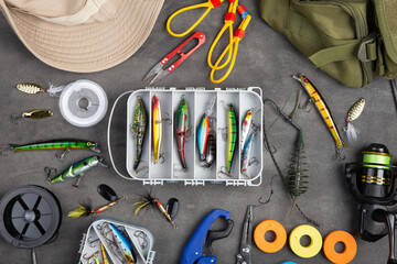 Fishing tackle - fishing spinning rod, hooks and lures on gray background. Active hobby recreation...